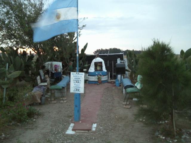 La bandera junto una leyenda que invita a cuidar a la virgen. Detrás la imagen.